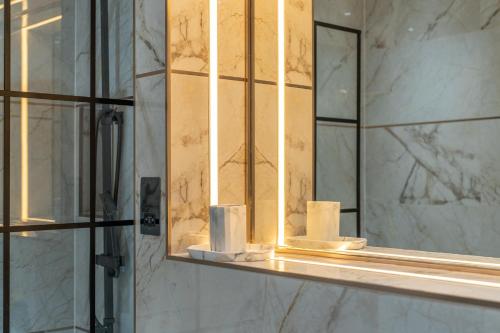 a bathroom mirror with rolls of toilet paper on a shelf at Canary Wharf Beautiful Modern House in London