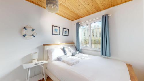 a bedroom with a white bed and a window at C15 Seamore, Riviere Towans in Hayle