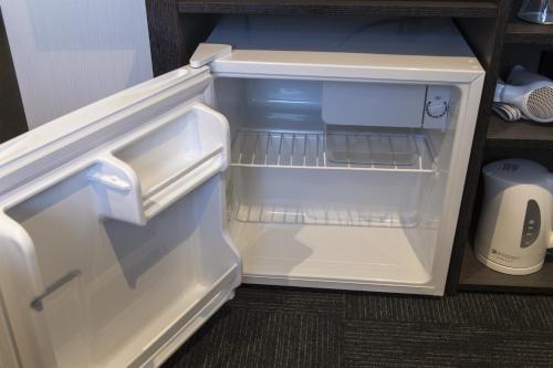 an empty refrigerator with its door open in a kitchen at Green Rich Hotel Hiroshima Shinkansenguchi (Artificial hot spring Futamata Yunohana) in Hiroshima