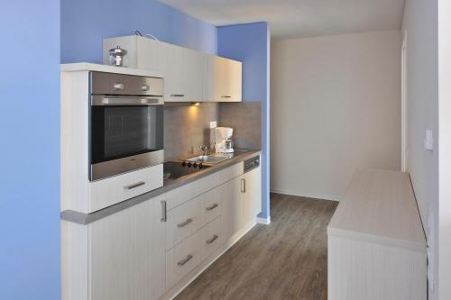 een keuken met witte kasten en een magnetron bij Apartmenthaus Hafenspitze Ap 21, Blickrichtung Binnenhafen NordOffenes Meer - a72367 in Eckernförde