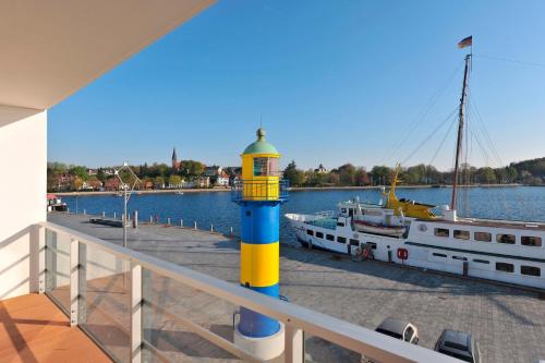 een gele en blauwe vuurtoren op een steiger met een boot bij Apartmenthaus Hafenspitze Ap 21, Blickrichtung Binnenhafen NordOffenes Meer - a72367 in Eckernförde