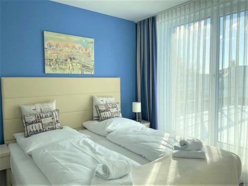 - une chambre avec 2 lits et un mur bleu dans l'établissement Apartmenthaus Hafenspitze Ap 37 "Sonnendeck", Blickrichtung von der Terrasse auf das Offenes Meer, Strand, Innenstadt, à Eckernförde