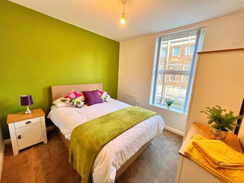 Dormitorio verde con cama y ventana en Bangor Central Apartments en Bangor