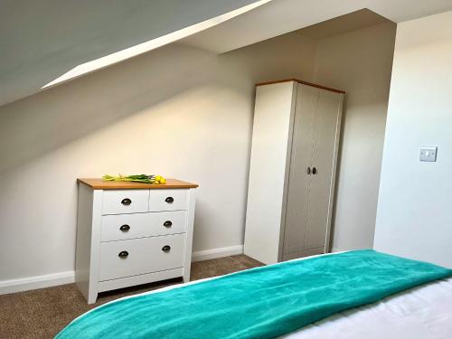 a attic bedroom with a bed and a dresser at Bangor Central Apartments in Bangor