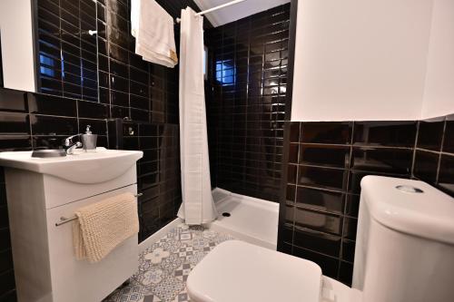 Baño de azulejos negros con aseo y lavamanos en 4 Mares Apartamentos M, en Loredo