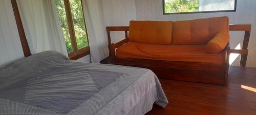 1 dormitorio con cama de color naranja y ventana en Cabaña La Colmena en Tigre