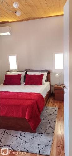 a bedroom with a large bed with red pillows at Quinta da Urtigueira in Felgueiras