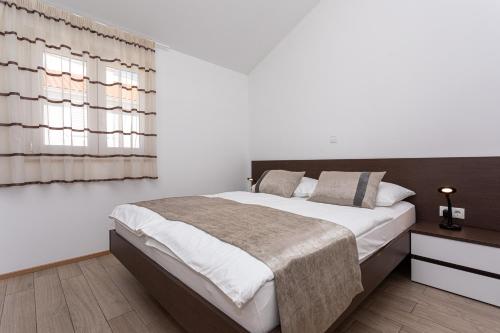 a bedroom with a large bed and a window at Apartments Crnekovic Tomislava 8 in Baška