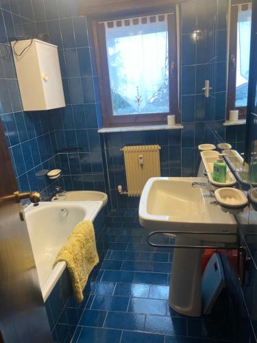 een blauw betegelde badkamer met een bad en een wastafel bij Enjoy Sauze d'Oulx in Sauze dʼOulx