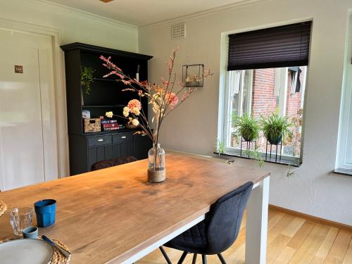 a dining room table with a vase of flowers on it at Bed and Breakfast De Beekhoek in Glane