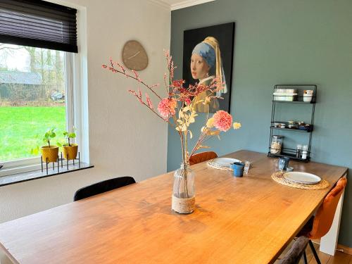 a dining room table with a vase with flowers in it at Bed and Breakfast De Beekhoek in Glane