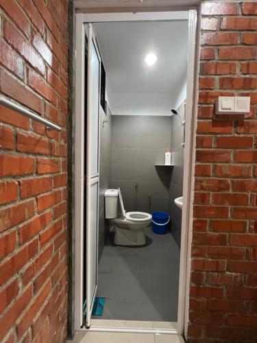 a bathroom with a toilet and a brick wall at Ujud Sepakat Homestay in Malacca