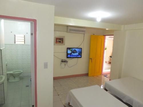 Habitación con baño y TV en la pared. en Constrell Pension House en Tagbilaran City