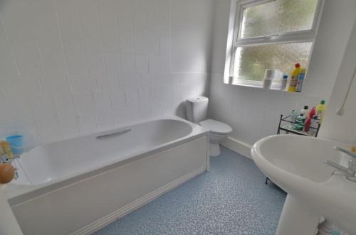 a bathroom with a tub and a toilet and a sink at Chycaron, Riviere Towans in Hayle