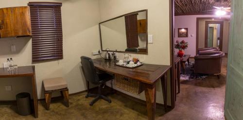 a room with a desk with a chair and a mirror at Emoya Basotho Lodge in Bloemfontein