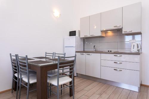a kitchen with a wooden table and white cabinets at Apartments Crnekovic Tomislava 8 in Baška