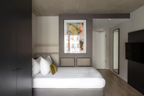 1 dormitorio con 1 cama blanca y una pintura en la pared en numa I Stark Rooms & Apartments en Múnich
