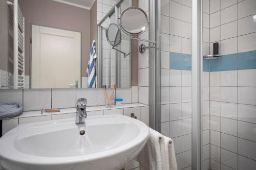 ein weißes Badezimmer mit Waschbecken und Spiegel in der Unterkunft TUI BLUE Sylt in Rantum