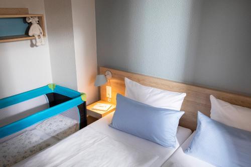 een slaapkamer met 2 bedden met witte lakens en een blauw hoofdeinde bij TUI BLUE Sylt in Rantum