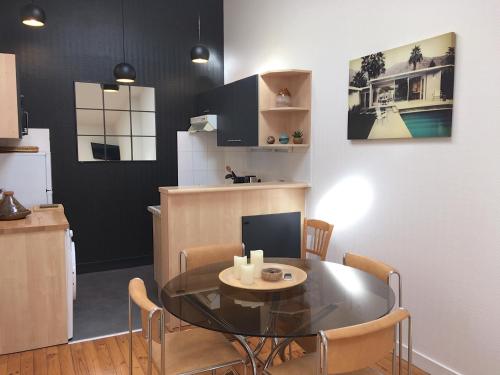 une cuisine et une salle à manger avec une table et des chaises en verre dans l'établissement Hotel de Ville 3 et Parking, à La Rochelle