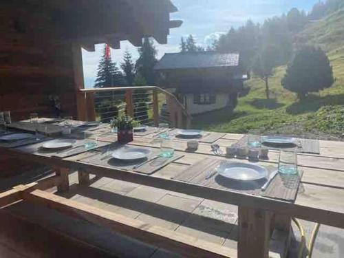 a wooden picnic table with plates on top of it at Ski in out Swiss Alps Chalet Charelle by Jolidi in Nendaz