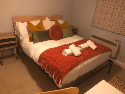 a bed with a red blanket and pillows on it at Maple by Paymán Club in Royston