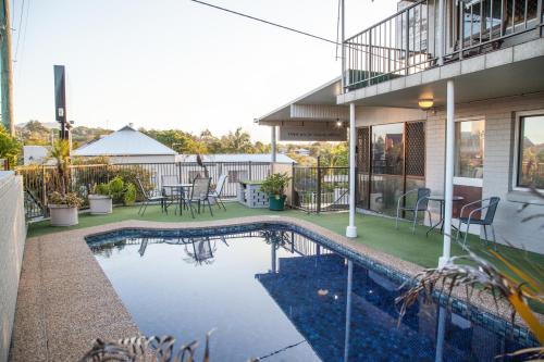 a pool with a pool table and chairs in front of a house at Murwillumbah Motor Inn in Murwillumbah