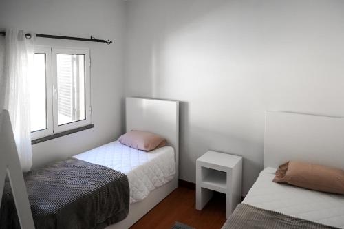um pequeno quarto com 2 camas e uma janela em Recanto da Madeira. em Ribeira Brava
