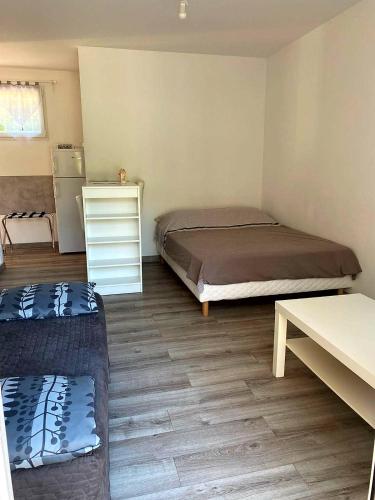a room with two beds and a table and a refrigerator at Studio calme près d’Aubagne in La Penne-sur-Huveaune