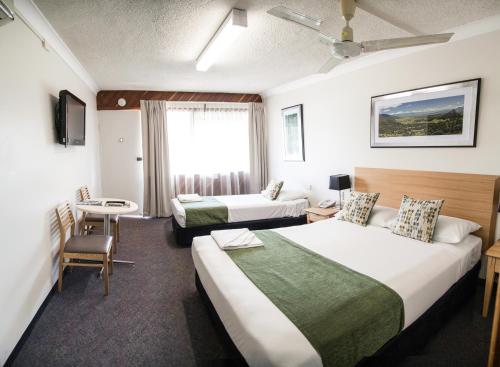 a hotel room with two beds and a table at Murwillumbah Motor Inn in Murwillumbah