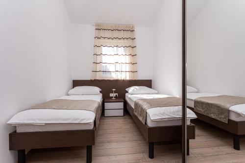 a bedroom with two beds and a mirror at Apartments Crnekovic Tomislava 8 in Baška