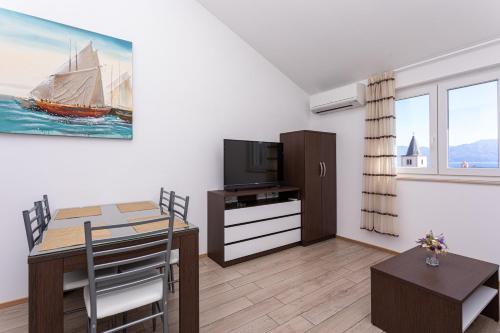 a living room with a dining table and a tv at Apartments Crnekovic Tomislava 8 in Baška