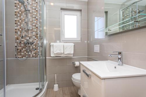 a bathroom with a toilet and a shower and a sink at Apartments Crnekovic Tomislava 8 in Baška
