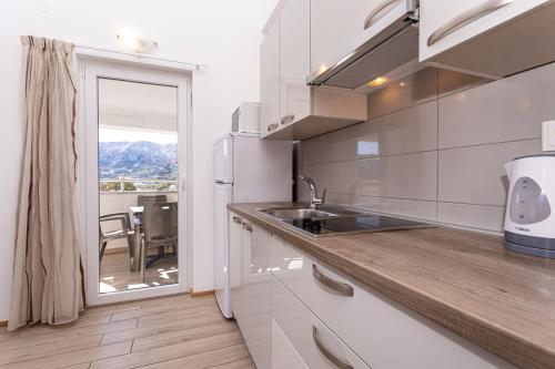 a kitchen with a sink and a view of a table at Apartments Crnekovic Tomislava 8 in Baška