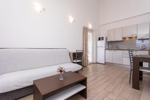 a living room with a white couch and a kitchen at Apartments Crnekovic Tomislava 8 in Baška