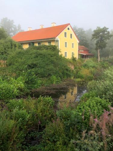 a yellow house on a hill next to a river at Tofvehults Boende in Skaftet