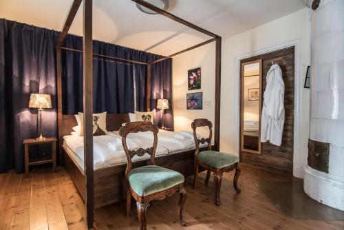 a bedroom with a four poster bed and two chairs at Bykrogen in Österslöv