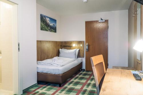 a small bedroom with a bed and a table at Gasthaus Kampenwand Bernau in Bernau am Chiemsee