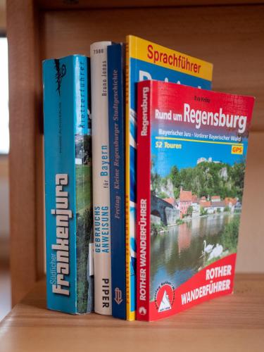 a row of books sitting on a shelf at Stifterfelsen Ferienwohnung in Sinzing