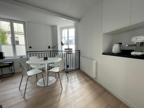 une chambre blanche avec une table et des chaises dans l'établissement le loft bleu - un atelier-cocon élégant & central, à Bordeaux