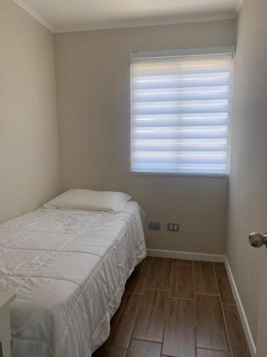um quarto branco com uma cama e uma janela em Senderos em Coquimbo