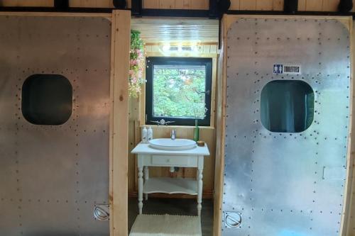 baño con lavabo blanco y ventana en Cottage romantique, son jacuzzi privatif, piscine en Rillieux