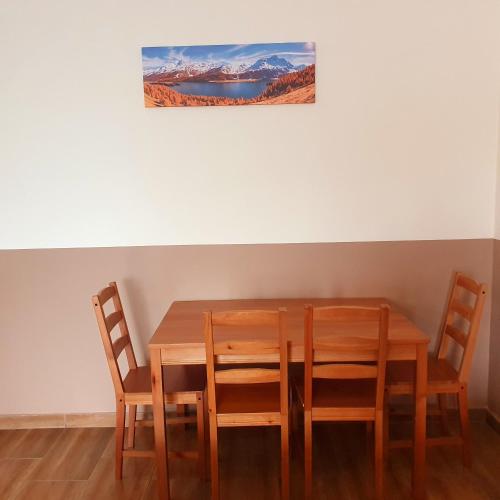 韋切什的住宿－Airport MicrostorePanzió，餐桌、四把椅子和墙上的绘画