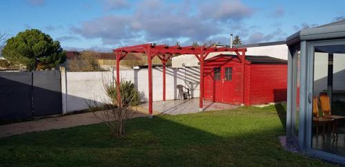 a red shed in a yard next to a fence at Gîte Les Galipes in Mareuil-sur-Ay