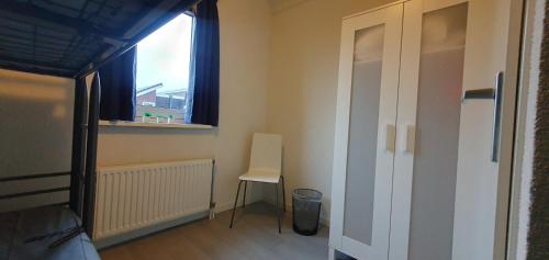 a bedroom with a bed and a chair and a window at Appartement Uniekappart in Uitgeest