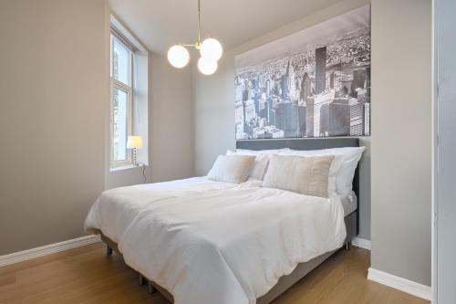 een witte slaapkamer met een groot bed met witte lakens bij Elegant Bergen City Center Apartment - Ideal for business or leisure travelers in Bergen