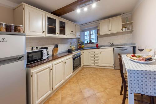 una cocina con armarios blancos y una mesa con un bol de fruta en Casa del Geco - La natura intorno a te en Camaiore