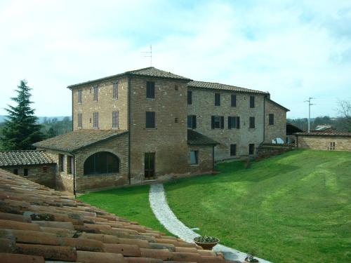 a large brick building with a grassy yard in front of it at Albergo La Foresteria in Bettolle