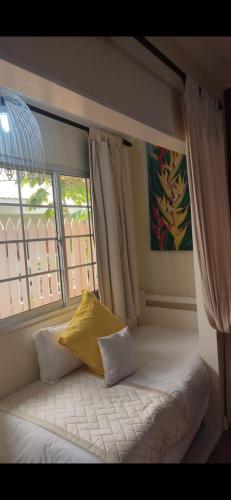 a bed with a yellow pillow in a room with a window at Oceane Self Catering in La Digue