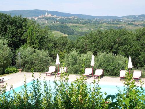 a pool with lounge chairs and a castle in the distance at Castello di Fulignano Sinadra superior apartment in San Gimignano